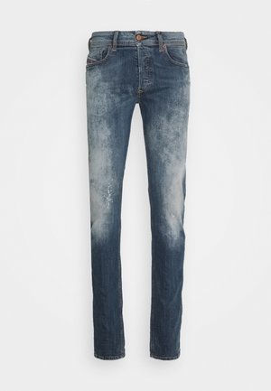 Slim-fit blue jeans with faded wash, button closure, and five-pocket design, displayed flat on a white background.