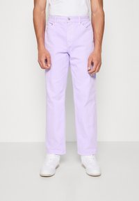 Světle fialové džíny z bavlny s přímým střihem, pětikapsovým designem a kovovým kováním. Nošeny s bílými teniskami a jednoduchým bílým tričkem.