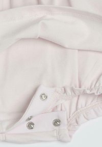 Body en coton doux rose clair, avec des pressions au bas, des accents de tissu froncé et des coutures plates le long des bords.