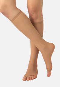 Beżowe, półprzezroczyste pończochy do kolan o gładkiej strukturze, z odkrytymi palcami oraz szerokim pasem u góry zapewniającym pewne dopasowanie.
