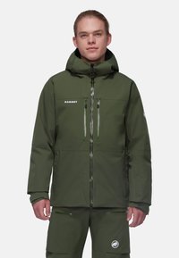 Giacca impermeabile verde con cappuccio, dotata di due tasche sul petto, chiusure con cerniera e un logo sul lato sinistro del petto. Tessuto dalla superficie liscia.