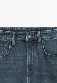 Denim jeans med en mørkeblå vask, et klassisk fem-lomme-design, metallknap og stikninger langs talje og lommer.