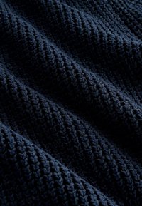 Donkerblauwe gestructureerde stof met een ribbelpatroon en verhoogde bubbels, wat een zachte, tastbare uitstraling creëert. Ideaal voor textiel of stoffering.