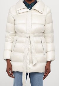 White padded coat with a belted waist, featuring a large collar, zippered pockets, and a smooth, glossy texture.