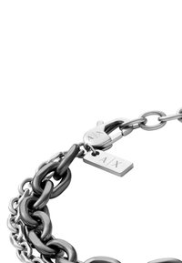 Kovový náramek se vzorem překrývajících se řetězových článků v lesklém a matném provedení, s bezpečnou sponou a štítkem označeným "A/X."