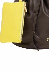 Borsa a secchiello in pelle marrone con una pochette gialla rimovibile. La pochette è dotata di una cerniera e dettagli in metallo dorato. Nodi notevoli sul cordino della borsa.