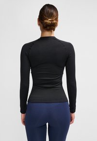 Langärmliges schwarzes Sportoberteil mit taillierter Passform, strukturiertem Stoff und rundem Ausschnitt, kombiniert mit marineblauen Leggings.