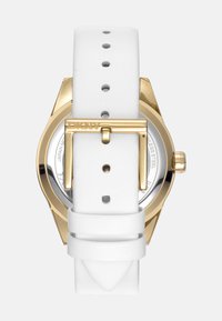 Orologio con cinturino in pelle bianca e cassa in acciaio inossidabile dorato. Presenta un quadrante rotondo e una chiusura con fibbia, mettendo in mostra un design minimalista.