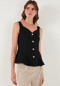 Schwarzes ärmelloses Oberteil mit V-Ausschnitt, fünf großen silbernen Knöpfen vorne und ausgestellt geschnittenem Saum; glattes Material und strukturiertes Design.