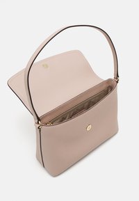 Sac à main en cuir beige avec une bandoulière unique, un rabat ouvert et un compartiment intérieur zippé avec des garnitures dorées.
