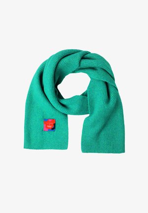 Turquoise geribbeld sjaal van zacht materiaal, met een rood en blauw label met de branding "TATUUM x Adeline Wong".