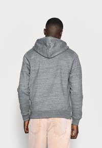 Grijze hoodie van een gestructureerde brei, met een voorzak en een capuchon. Geribbelde boorden en onderkant met een ontspannen pasvorm.