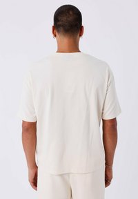 Crème-kleurig t-shirt met korte mouwen en een relaxte pasvorm, gemaakt van zachte materialen, met een klassieke ronde halslijn en vlakke naden.