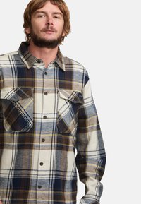 Flanelle hemd in blauw, roomkleur en bruin ruitpatroon, met twee borstzakken en een knoopsluiting aan de voorkant met een klassieke kraag.