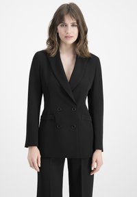 Black double-breasted blazer with a V-neck, long sleeves, two front pockets, and black buttons. Smooth, tailored fabric with a structured design.