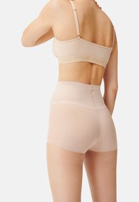 Nahtlose, hohe Shapewear-Shorts ohne Nähte in Hautfarbe mit glatter Textur, vollständiger Abdeckung und elastischem Bund. Inklusive verstellbarer Träger am BH.