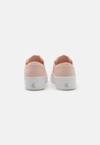 Różowe płócienne buty wsuwane z białą gumową podeszwą, z logo z tyłu, gładką fakturą i okrągłym noskiem.