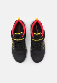 Black athletic shoes with mesh upper, yellow accents, red interior lining, and a white sole. Features a padded ankle and lace-up design.