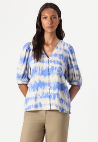 Blå og beige tie-dye bluse med korte puffermer, V-hals og knapper nedover forsiden. Mykt, strukturert stoff med en avslappet passform.