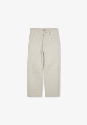 Pantalons en coton beige avec des coutures visibles, deux poches avant et une fermeture à bouton. Présente des petits points décoratifs sur le tissu.