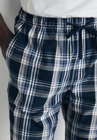 Shorts à carreaux dans des couleurs marine, gris et blanc, avec une taille élastique à cordon de serrage et des poches latérales.