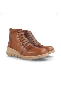 Botas de tobillo de cuero marrón con un diseño texturizado, que cuentan con cordones grises en zigzag, un cierre lateral y una suela de cuña beige.