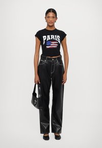 Black cropped t-shirt with white "PARIS" text and striped flag graphic, paired with high-waisted black leather wide-leg pants.