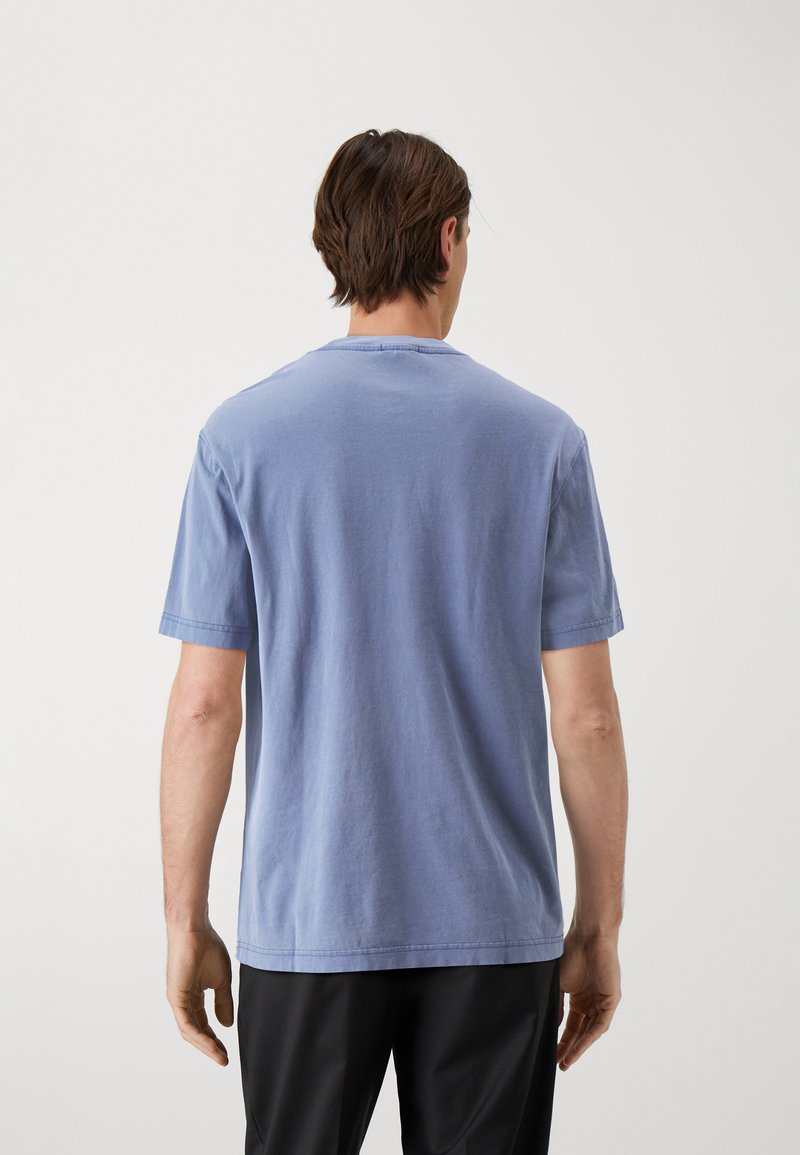 Camiseta de algodón de color azul claro con cuello redondo, mangas cortas y un ajuste relajado. Textura suave y detalles de costura mínimos en las costuras.