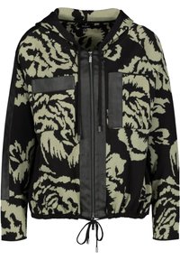 Chaqueta de gran tamaño en negro y oliva con un patrón floral, que cuenta con cierre de cremallera en la parte delantera, dos bolsillos en el pecho y un dobladillo elástico con cordones.
