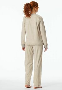 Beige loungewear set featuring a long-sleeve top with ribbed cuffs and matching pants with a relaxed fit, made from soft, textured fabric.