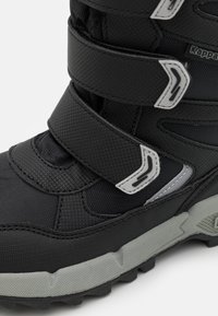 Schwarze Winterstiefel mit strukturiertem Synthetik-Obermaterial, drei verstellbaren Klettverschlüssen und einer grauen Gummisohle mit tiefen Profilen für bessere Haftung.