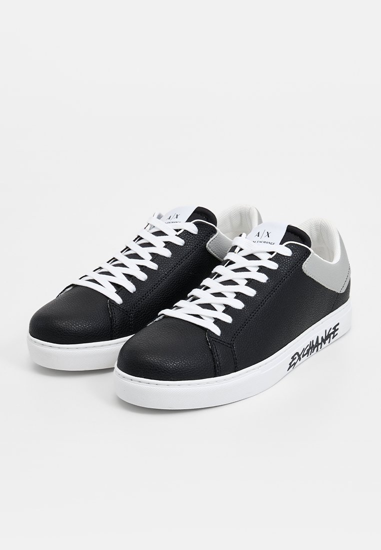 Czarne skórzane sneakersy z białymi sznurówkami i podeszwą. Teksturowana cholewka oraz szare akcenty w okolicy pięty. Na boku napis "EXCHANGE".