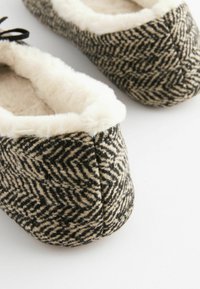 Black and beige houndstooth pattern slippers with a soft beige faux fur lining and ribbon accents at the top, featuring a rounded toe design.