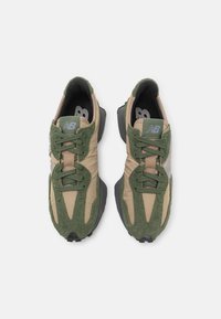 Sneaker verde e beige con un mix di materiali scamosciati e tessili, suole in gomma nera e cuciture dettagliate.