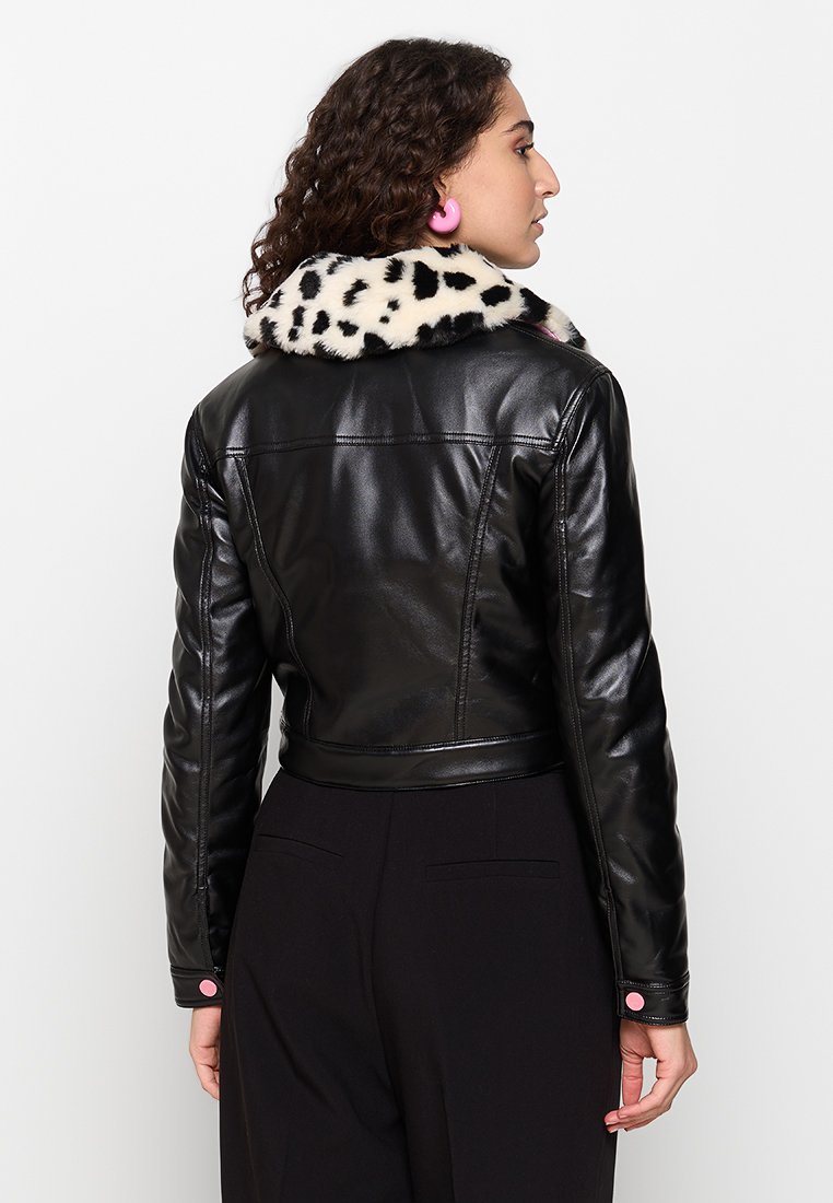Schwarze, cropped Lederjacke mit einem gepunkteten Kunstfellkragen. Sie hat eine taillierte Passform, lange Ärmel und rosa Knopfdetails an den Ärmelbündchen.