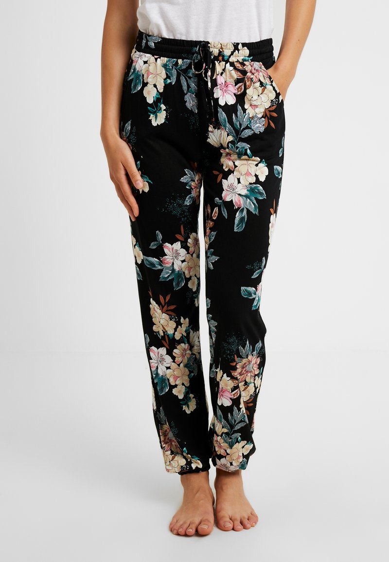 Zwarte loungebroek met bloemenpatroon, voorzien van een elastische taille, trekkoordsluiting en zakken. Gemaakt van lichtgewicht, zachte stof.