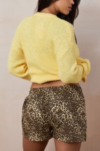 Yellow, fluffy sweater with a rounded neckline paired with leopard-print shorts featuring a brown base and light gold accents.