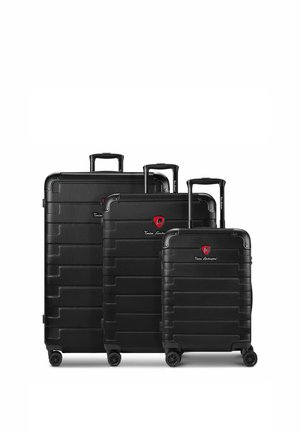 Drie zwarte harde koffers met uitschuifbare handvatten en vier wielen, gerangschikt in aflopende grootte, met een rood logo en merknaam.