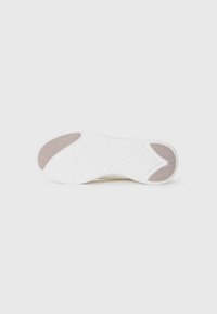 Sole of a white sneaker with textured tread and beige grip pads on heel and toe areas on a white background.