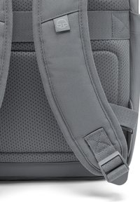 Grå ryggsäck med vadderade meshremmar, texturerad yta, justerbara clips och ett logomärke. Har en elegant design för komfort och stöd.