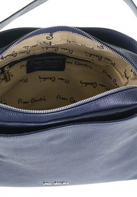 Borsa in pelle di colore blu navy, con una finitura testurizzata. L'apertura con zip rivela un interno beige con un motivo stampato a logo e scomparti.