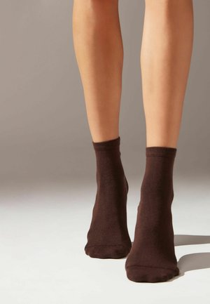Braune Knöchel-Socken aus weichem Material, mit einer glatten Textur und einem schlichten Design. Es sind keine Muster oder Metallteile vorhanden.