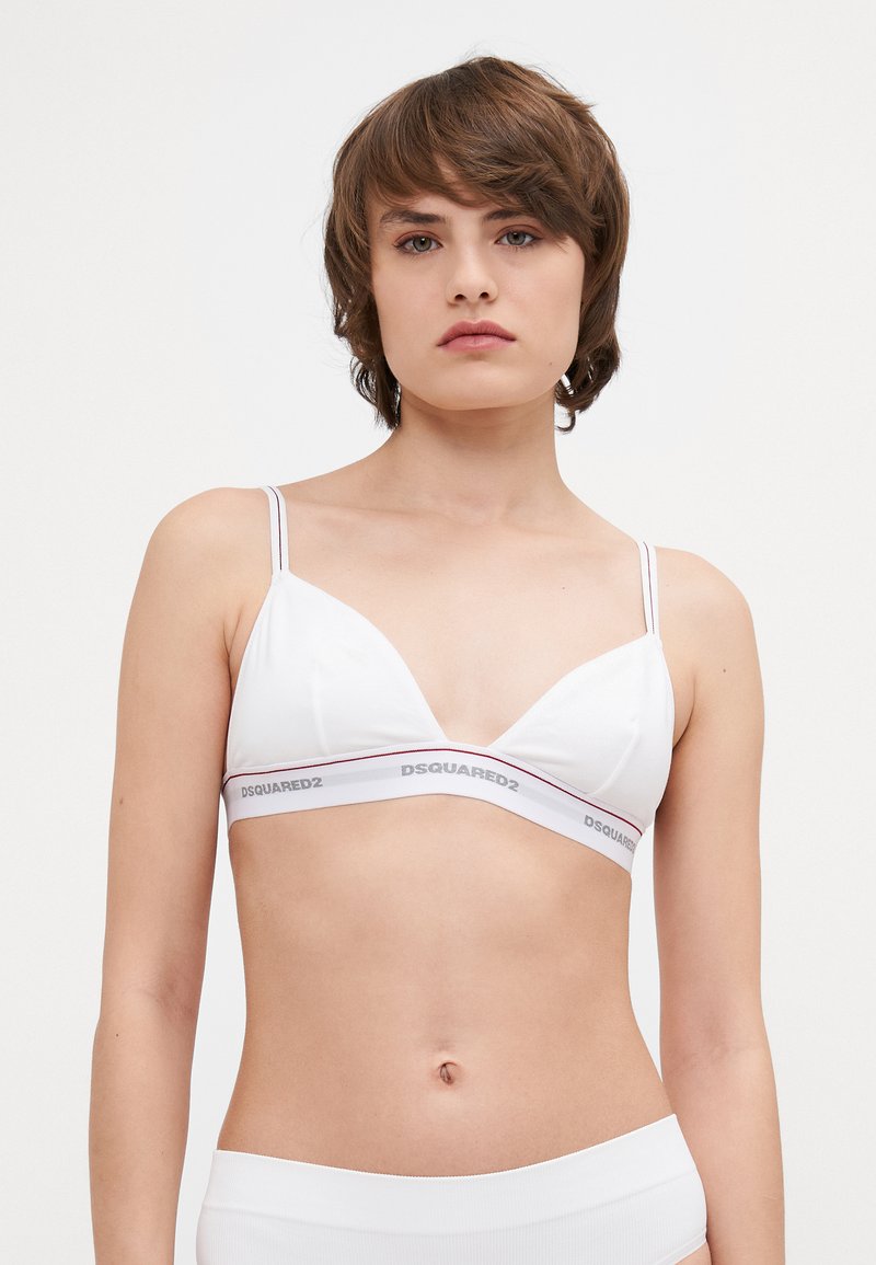 Hvid trekantet bralette lavet af glat stof, med tynde stropper og et mærke-bånd med røde accenter. Enkelt design uden polstring.