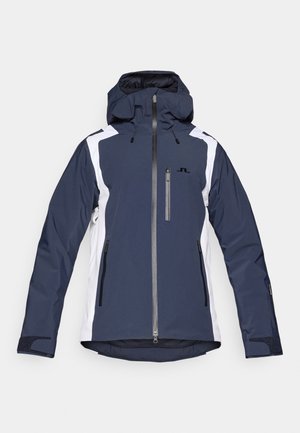 Tumesinine suusajakiga valge aktsentidega, millel on kapuuts, esikinnitatud lukk, kaks küljetaskut ja reguleeritavad mansetid. Valmistatud vastupidavast materjalist.