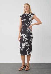 Rochie neagră cu imprimeu floral alb, design ajustat, măneci scurte, lungime până la genunchi, material elastic, asortată cu sandale negre cu barete.