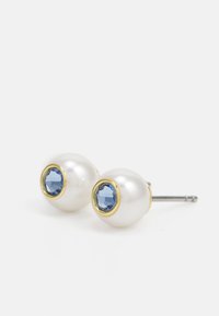 Boucles d'oreilles en perles avec une surface blanche lisse, mettant en vedette une pierre précieuse bleue ronde entourée d'une monture en ton doré.