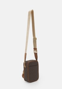 Piccola borsa a tracolla rettangolare marrone con motivo a logo MK ripetuto, rifiniture beige, zip dorata e tracolla in tessuto beige regolabile.