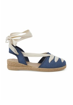 Espadrille de lona azul con tiras crema, plantilla de yute trenzado, diseño de talón abierto y detalles de tiras entrelazadas en el antepié.
