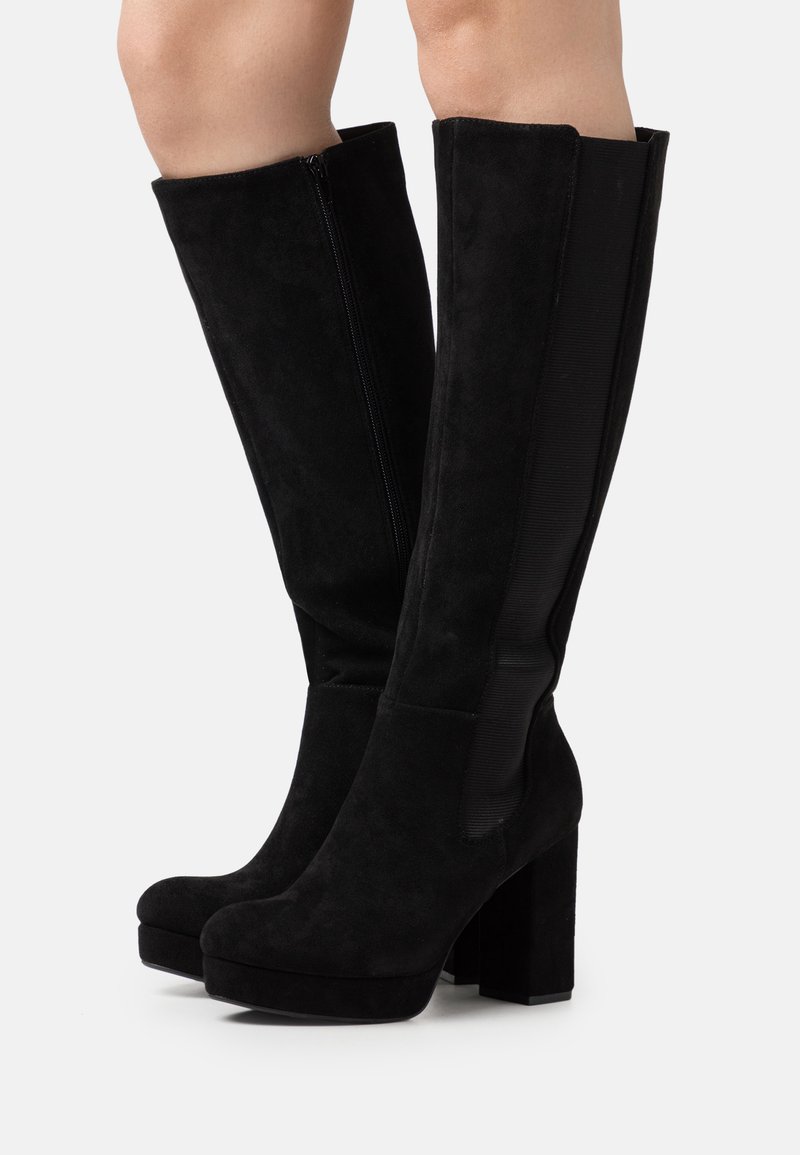 Stivali neri al ginocchio in suede con tacco spesso, dotati di zip laterale e pannello elastico per una vestibilità aderente. Texture liscia.