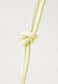 Yellow leather strap with a knot and decorative stitching. Smooth texture, flexible shape, and consistent color throughout.